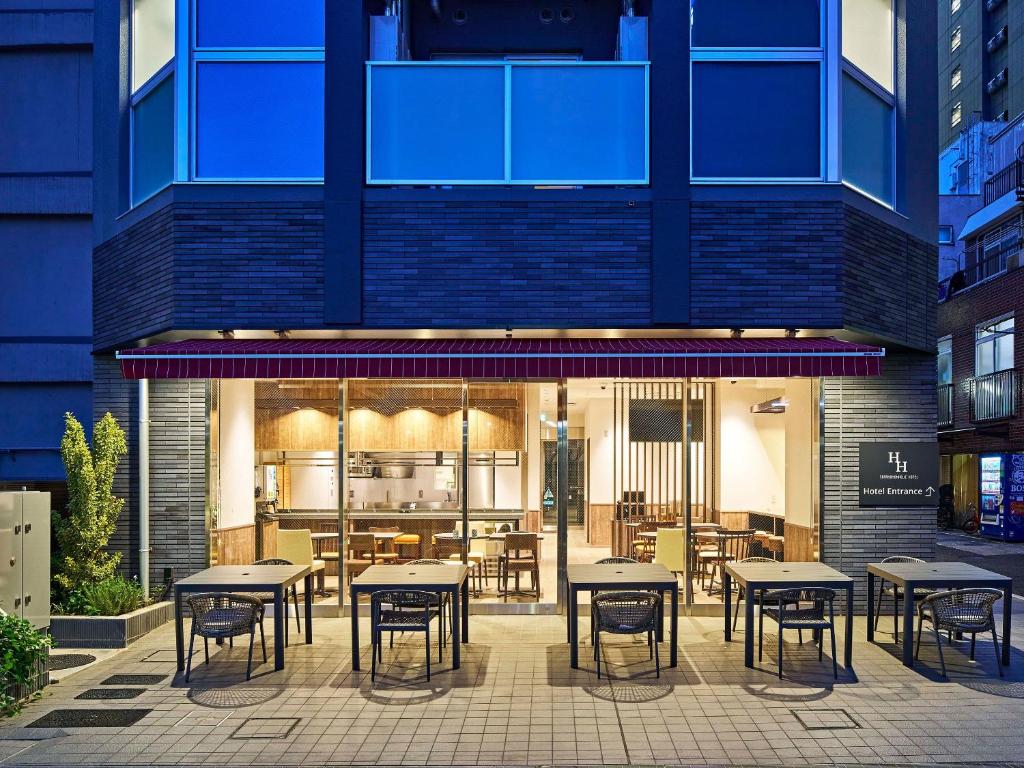 a restaurant with tables and chairs in front of a building at TORANOMONHOLIC Hotel in Tokyo