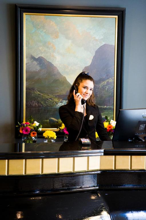 a woman talking on a phone at a desk with a laptop at Scott's Hotel in Killarney