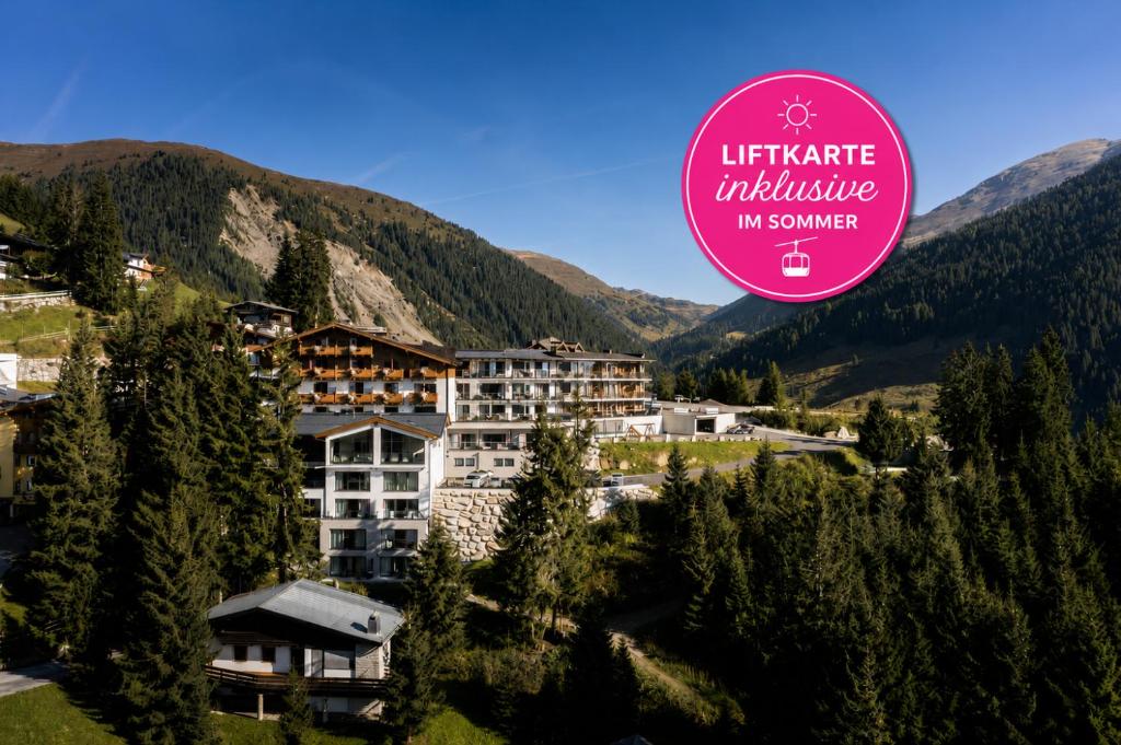 a hotel in the mountains with a sign on it at Ursprung Panorama Hotel Königsleiten in Königsleiten