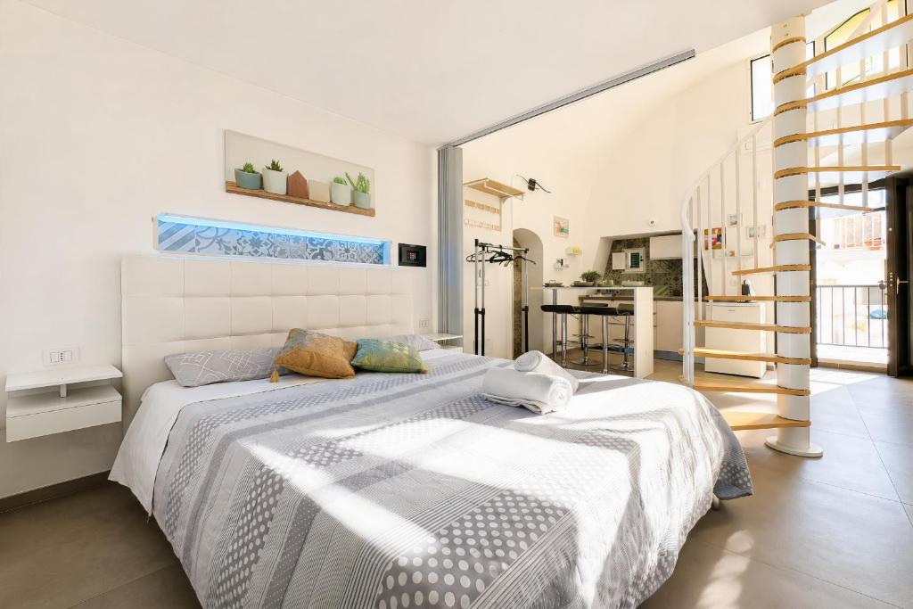 a white bedroom with a large bed and a kitchen at Venti Nodi in Vieste