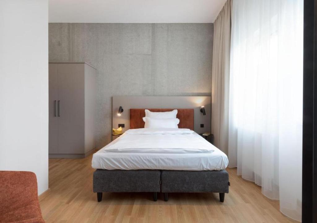 a bedroom with a large bed with white sheets at Brera Serviced Apartments Singen in Singen