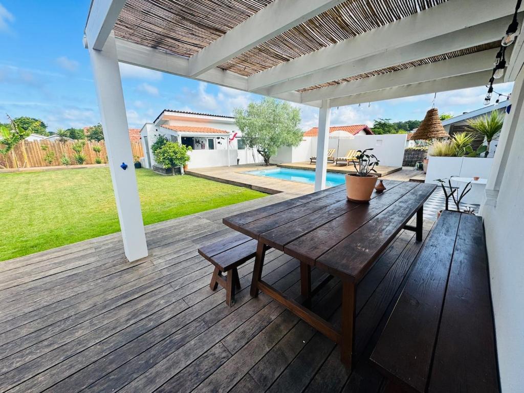 a wooden deck with a table and a pool at Villa between forest and ocean in Labenne