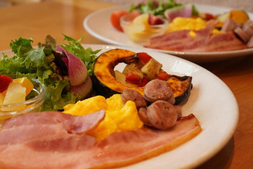 two plates of food on a wooden table at BRENZA HOTEL in Kobe