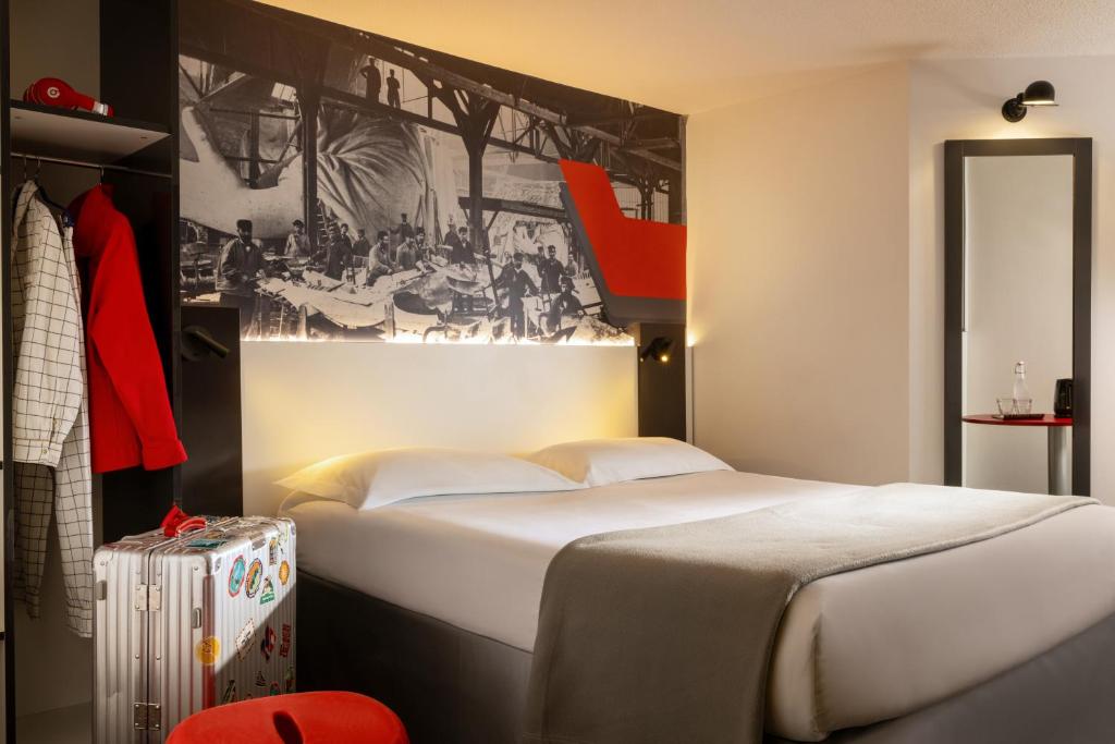 a bedroom with a large bed and a painting on the wall at Hôtel Gustave Colmar in Colmar