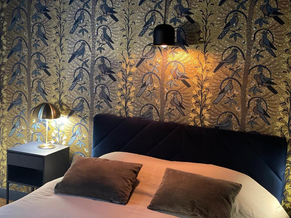 a bedroom with a bed with a patterned wall at Au petit Chapeau Rouge in Clisson