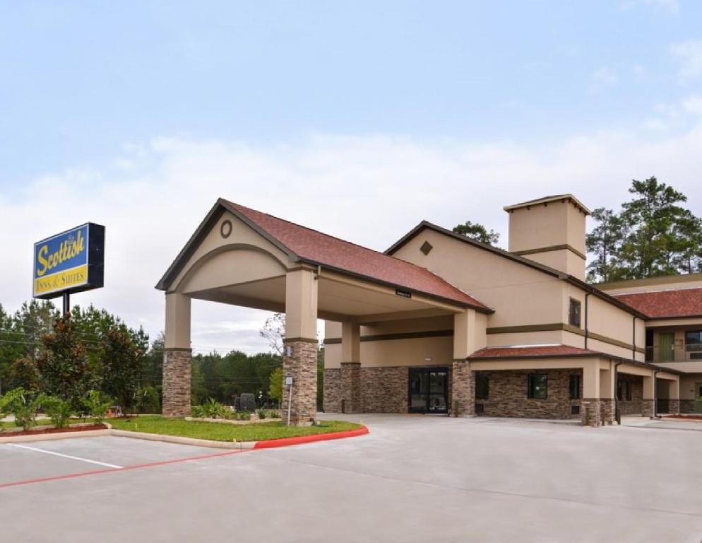 uma vista frontal de um hotel com estacionamento em Scottish Inn & Suites - Conroe em Conroe