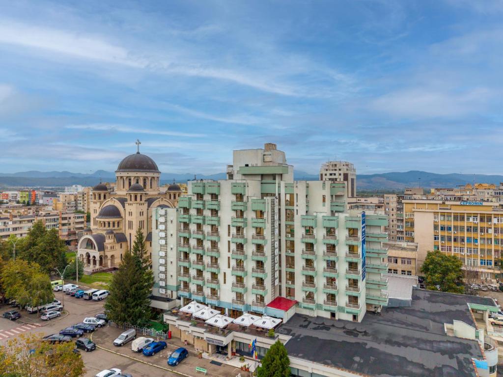 a large building in a city with a parking lot at Hotel Sarmis in Deva