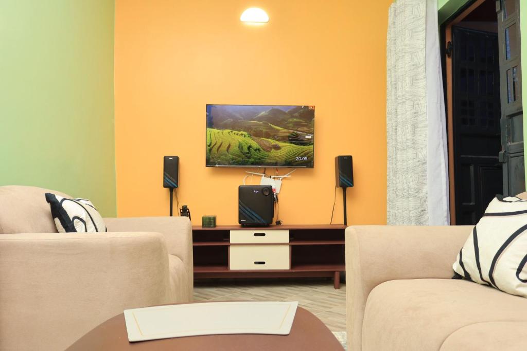 a living room with two chairs and a flat screen tv at BomaZuri Homestays Tala in Nguluni