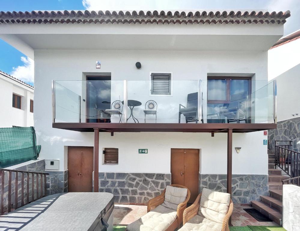 a glass house with two chairs on a balcony at Casa Maruca with Roque Nublo view in Tejeda
