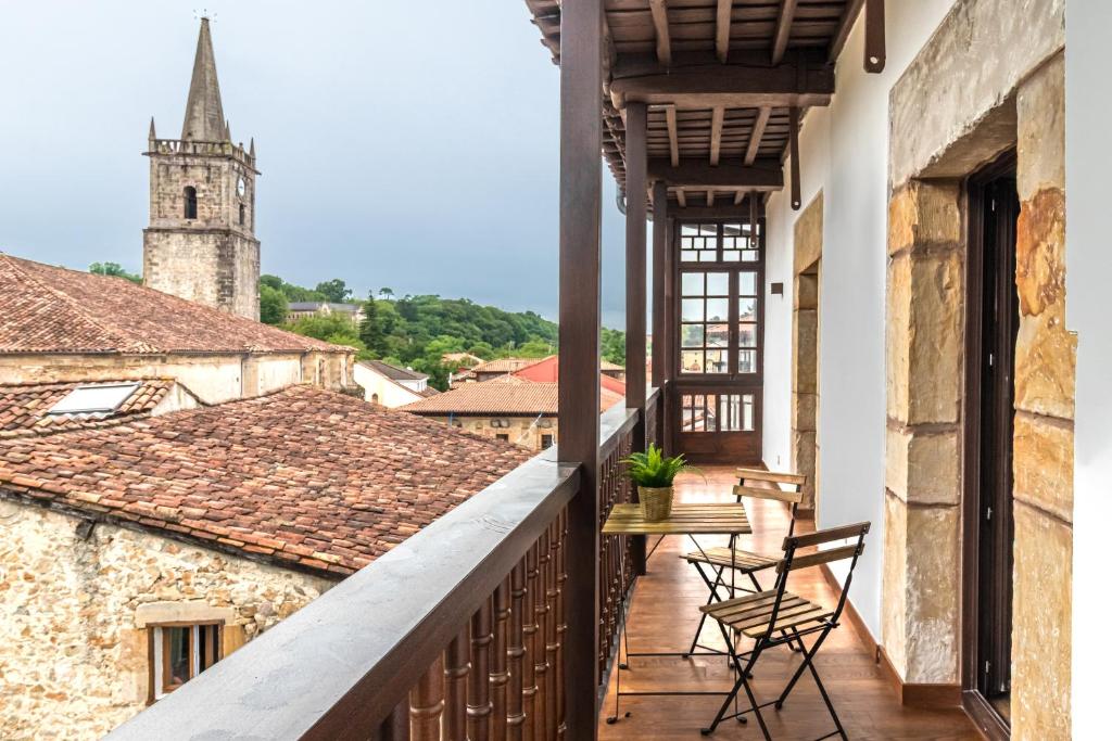 a balcony with chairs and a view of a church at Apartamentos La Botica in Comillas