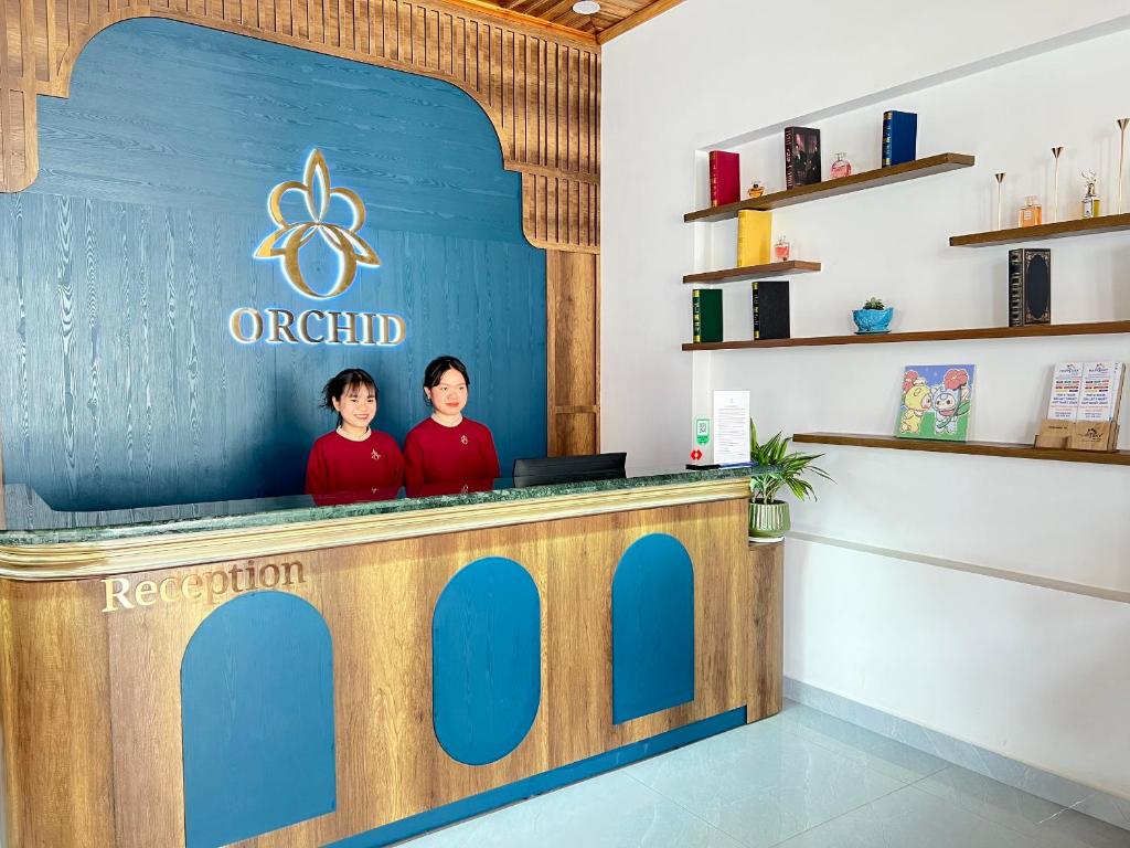 two people standing at a counter in a restaurant at ORCHID Hotel in Da Lat