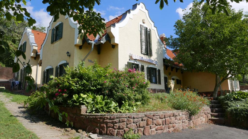 een huis met een stenen muur en bloemen ervoor bij Hillside Apartments in Révfülöp