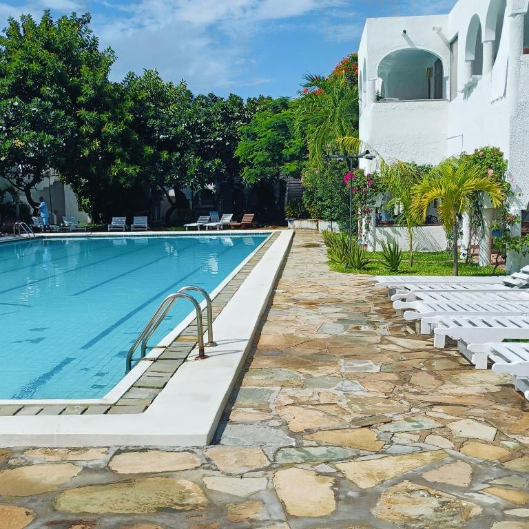 a swimming pool with chairs next to a building at Summer Studio Suit in Malindi