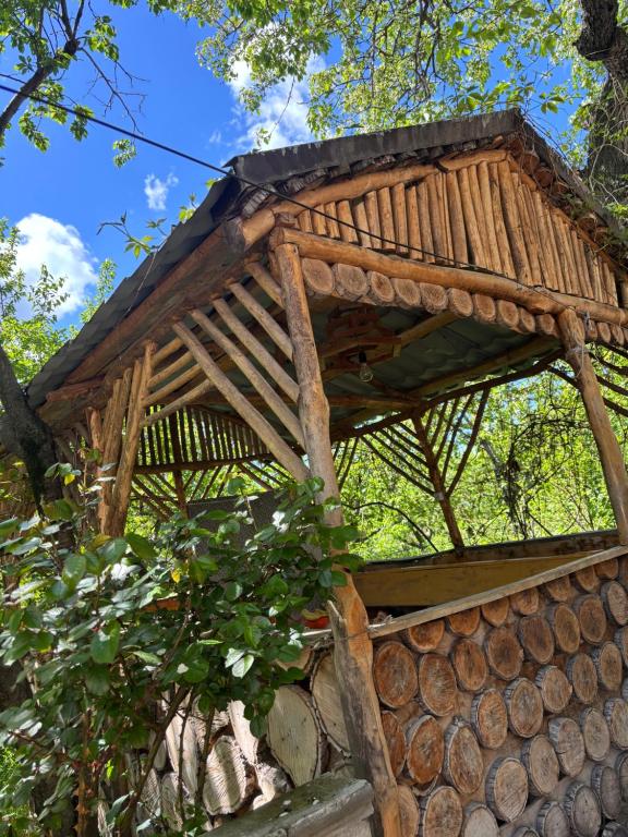 a tree house with a roof on a pile of logs at Lucy Guest House in Garni