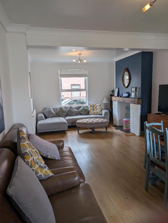 a living room with a leather couch and a table at Spacious 3 bed house near beach! in Lowestoft