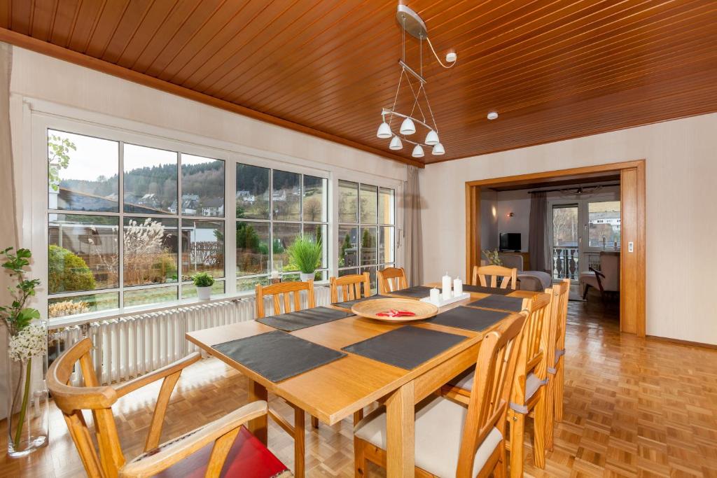 a dining room with a table and chairs and windows at Ferienhaus Willkommen in Winterberg