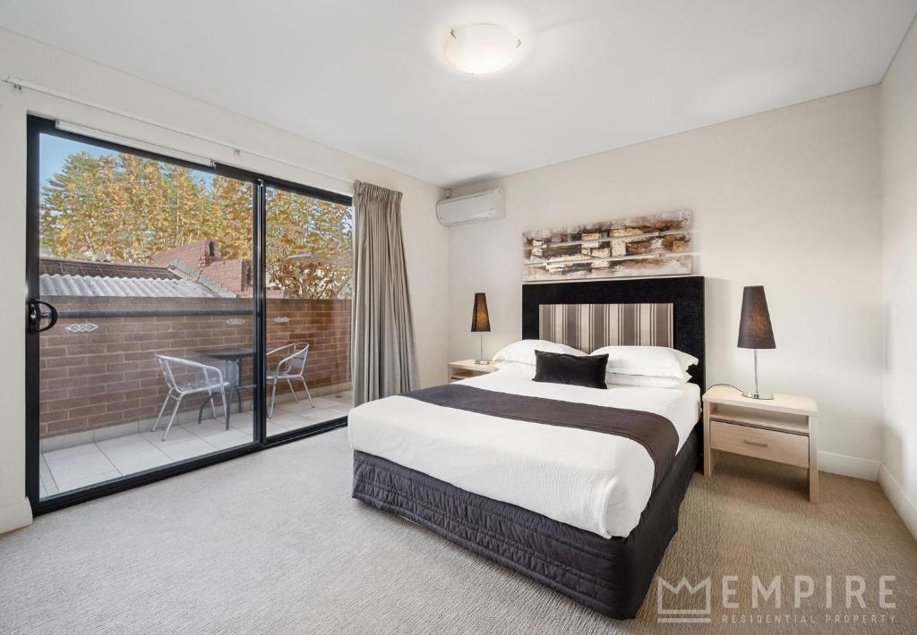 a bedroom with a large bed and a balcony at Parklane Apartments in Fremantle