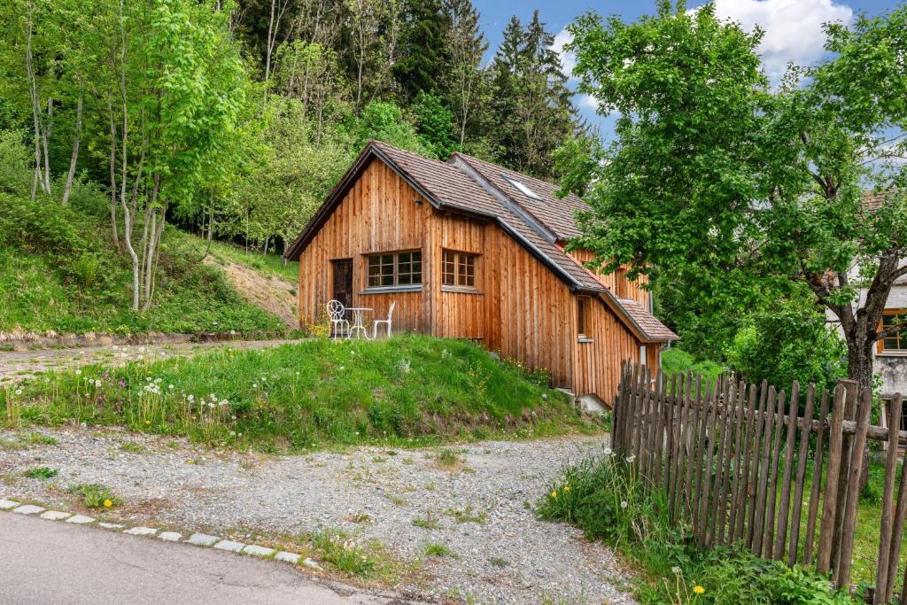 a wooden house with a fence next to a road at Hofgut Heiligenberg in Heiligenberg