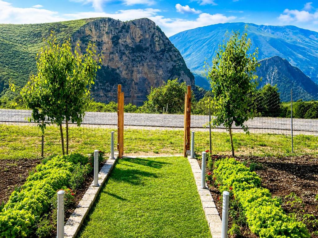 a garden with trees and grass and mountains in the background at Vatra Traditional Guesthouse in Lekdush