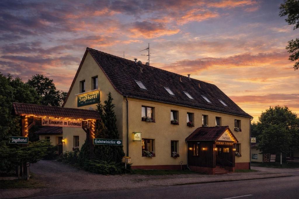 a building on the side of a street with a sunset at Jagdhotel am Strehlesee in Wandlitz