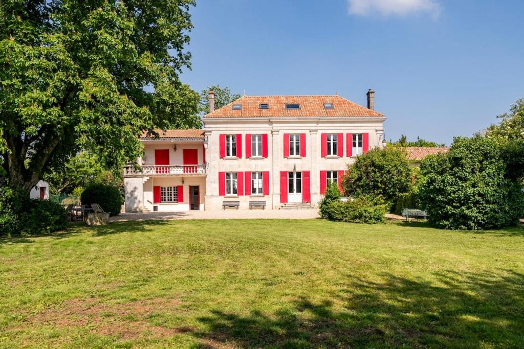 a large house with red windows and a large yard at Maison de famille au coeur de son vignoble in Lorignac
