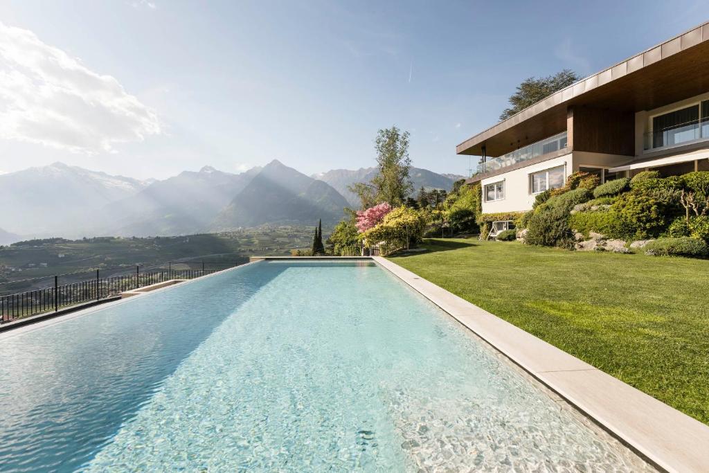 a swimming pool in front of a house with mountains at Schenna Chalet - Chalet Oasis in Schenna