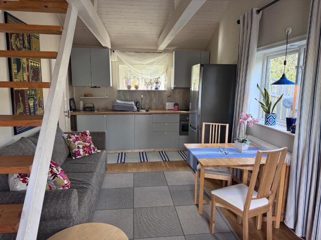 a kitchen and living room with a table and a couch at Mysig lägenhet med morgondopp in Uppsala