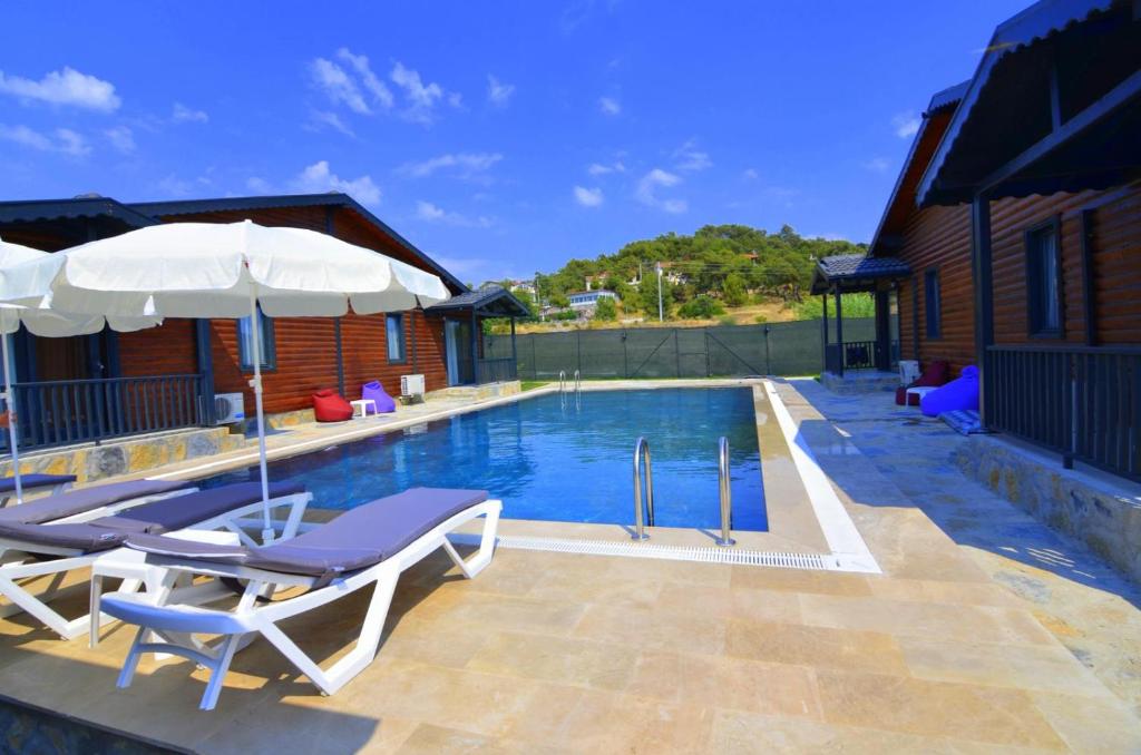 a swimming pool with chairs and umbrellas next to a house at Summertime Bungalows in Fethiye