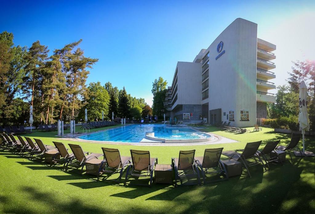 a group of chairs sitting in the grass in front of a building at Ensana Esplanade in Piešťany