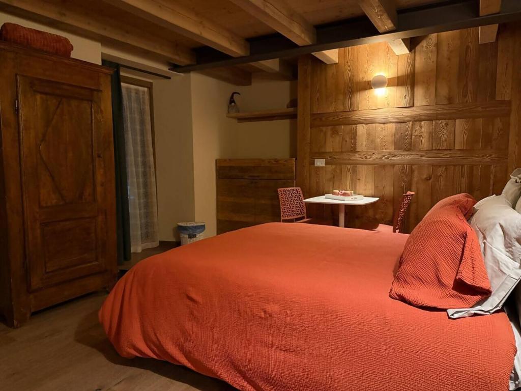 ein Schlafzimmer mit einem Bett mit einer orangefarbenen Decke und einem Tisch in der Unterkunft La Brenva Morgex in Morgex
