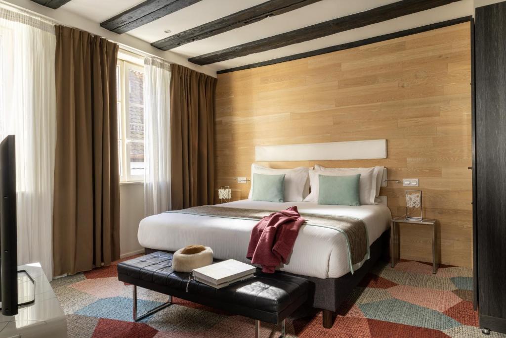 a bedroom with a bed and a table with books at Hotel Le Colombier Suites in Colmar