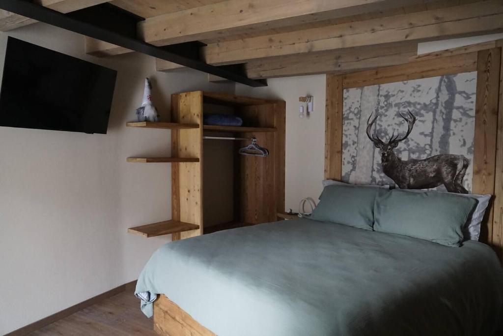 a bedroom with a bed with a tv and a deer on the wall at La Becca Morgex in Morgex