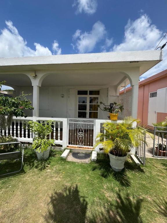 a house with a white fence and some plants at MAISON DE VACANCES KAZ A LOLO in Port-Louis