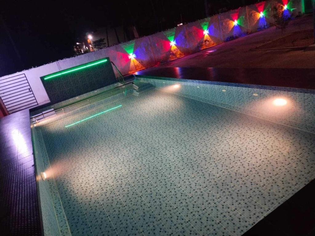 a pool with lights on top of it at night at Hotel O CANARIES RETIREES RESIDENCY in Kottakupam