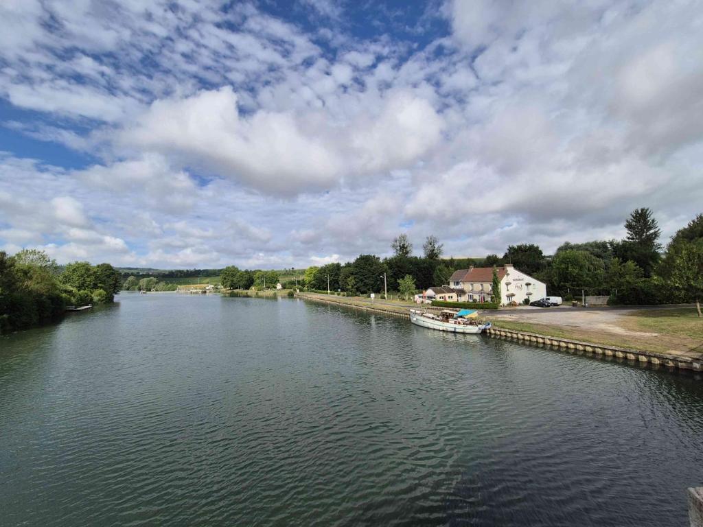 a river with a house and a boat in the water at Entre 2 Rives in Charly-sur-Marne