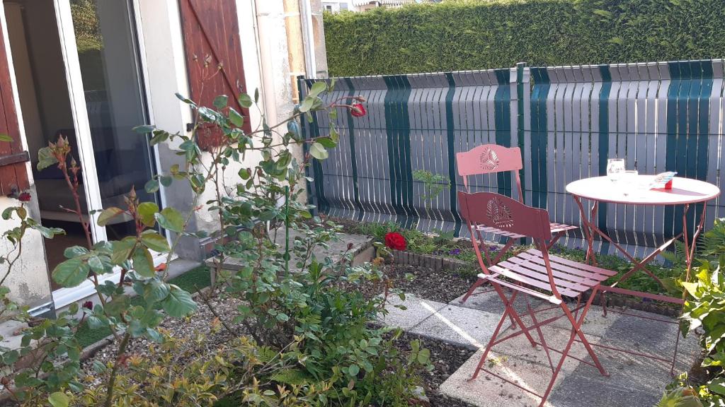 a red chair and a table in a garden at Entre Golf et Mer RDC in Dieppe
