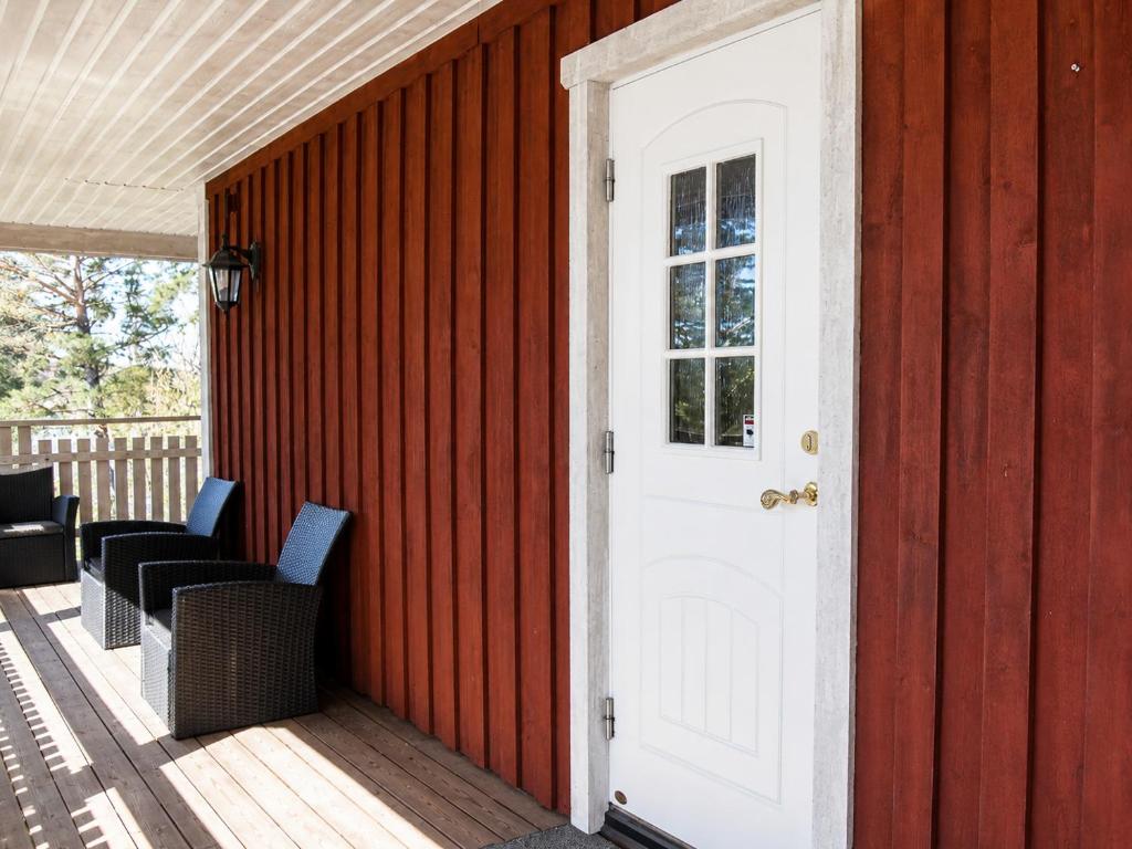 a white door on a red house with two chairs at Solbacka Apartment in Södra Ås