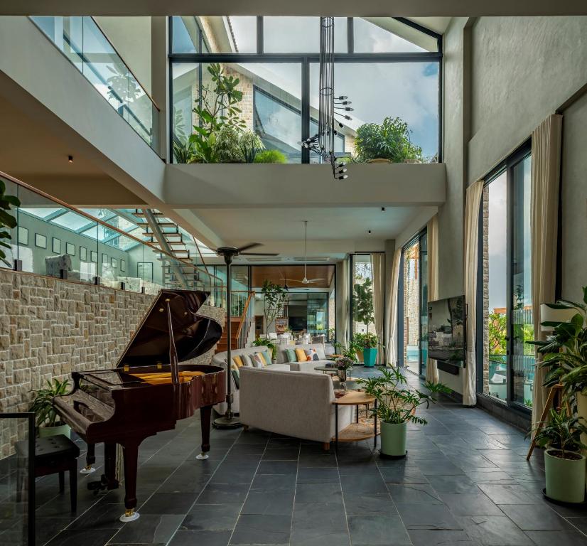 an indoor living room with a piano and a couch at SaffronStays Citadel in Sangolda