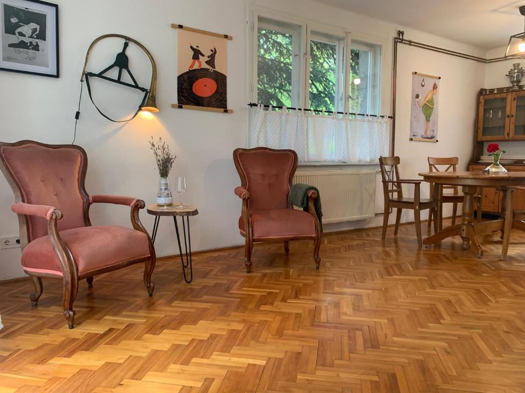 a living room with chairs and a wooden floor at Tūlevél/Pine-needles in Tata
