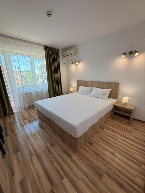 a bedroom with a large bed and wooden floors at Steluta in Eforie Nord