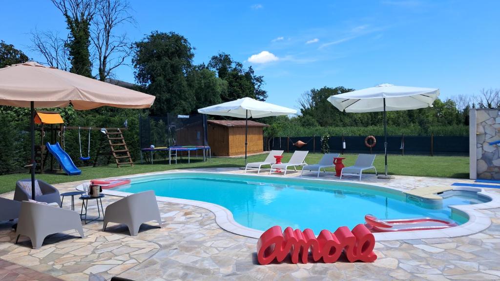 a swimming pool with chairs and umbrellas at Villa Posta Vecchia in Loreo