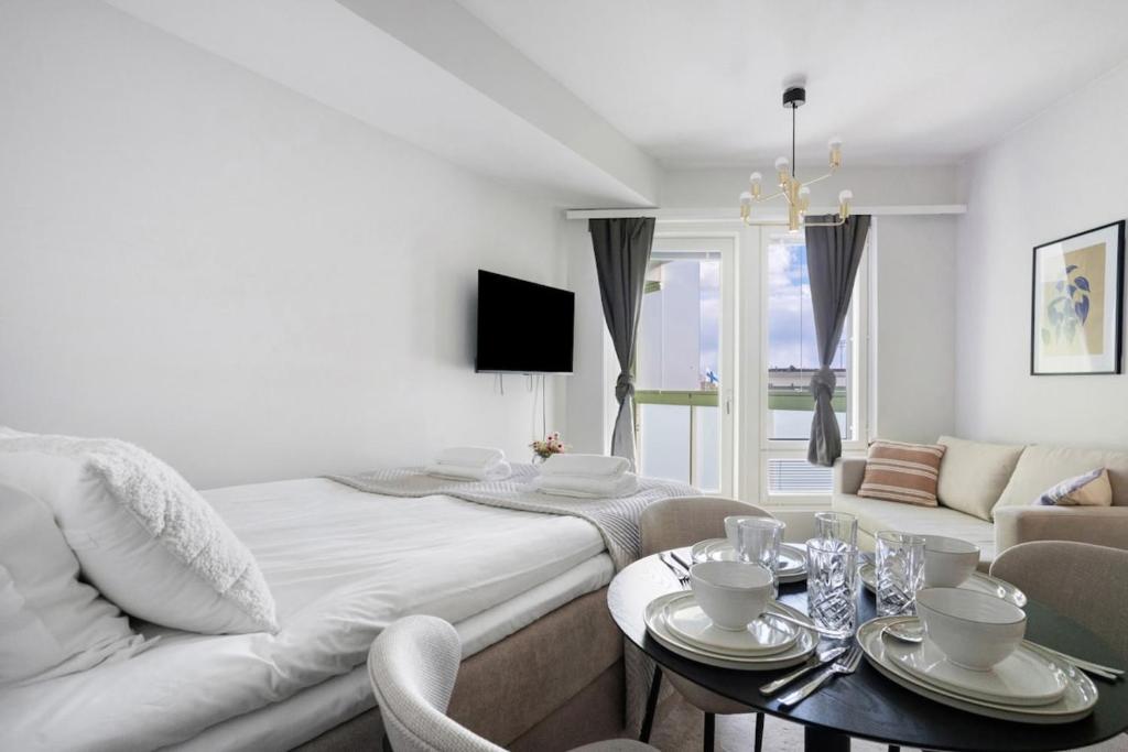 a white room with a bed and a couch and a table at Modern Arctic Studio By Lapland Host in Rovaniemi