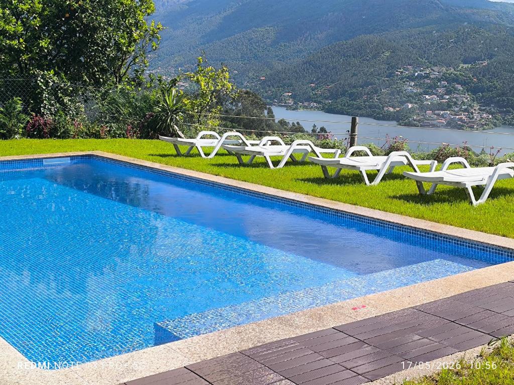 a swimming pool with white chairs and a view of a mountain at Casa Sambinho II Bela Vista in Rio Caldo