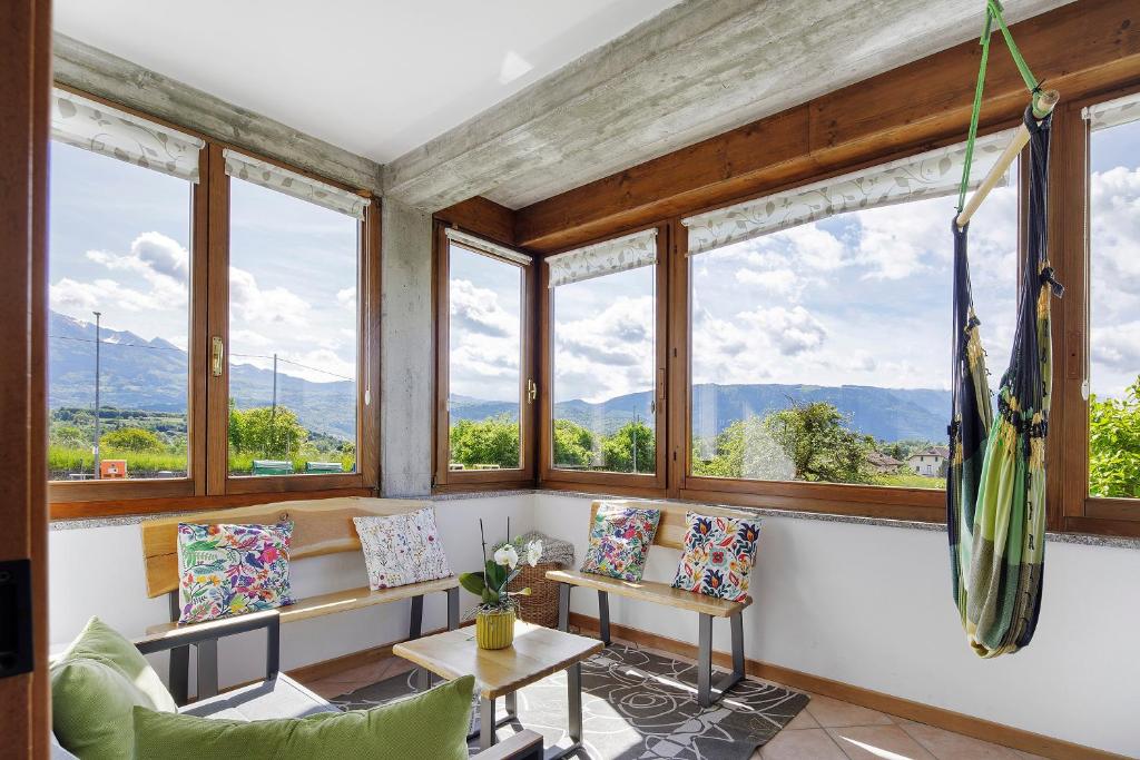 a room with windows and chairs with mountains in the background at La Veranda - Alpago in Pieve dʼAlpago