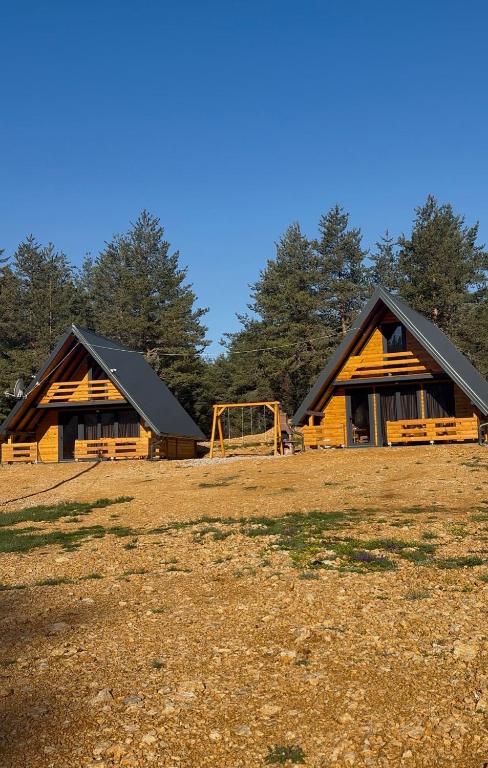 two large wooden buildings with a playground in a field at ROMANIJA vikendice in Sarajevo