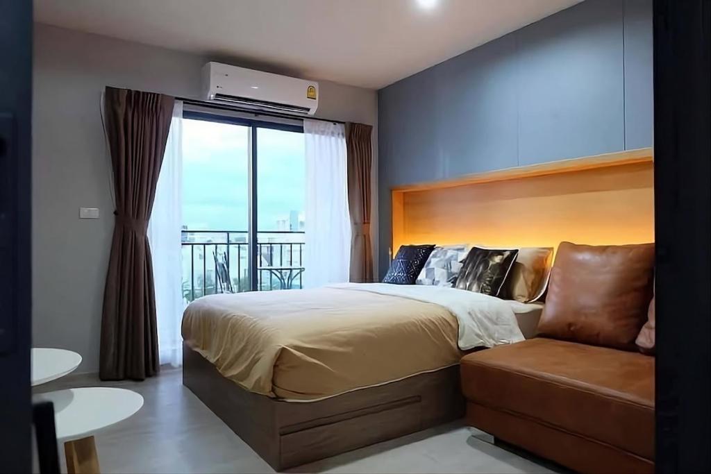 a bedroom with a bed and a couch and a window at Exclusive Condo with Pool - Self Check-in in Hua Hin
