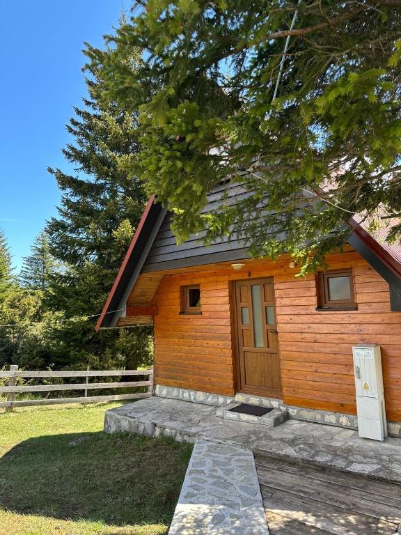 a wooden cabin with a door and a fence at Bungalows Krstajić in Žabljak