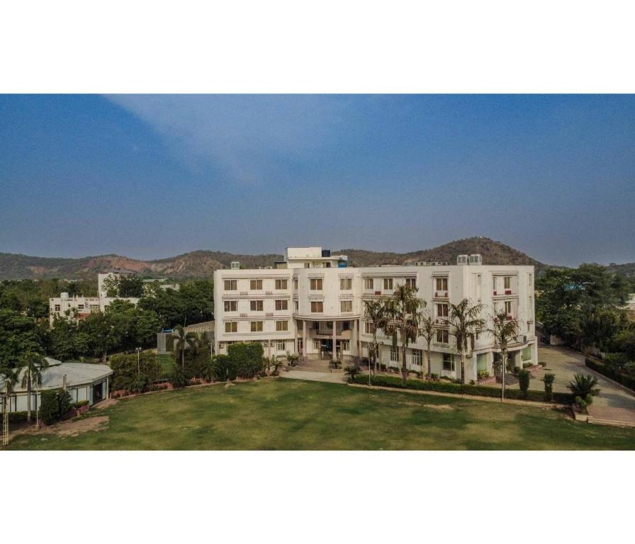 a large white building with palm trees in front of it at Sagar Resort in Alwar