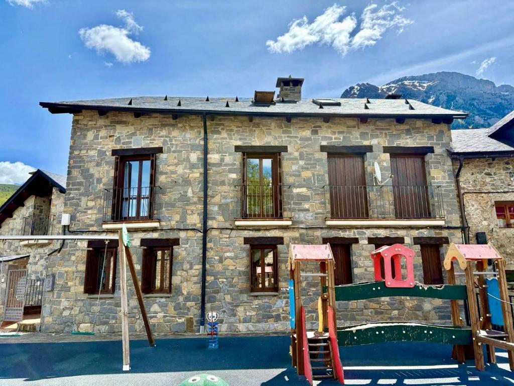 a stone building with a playground in front of it at Casa Miradell in Hoz de Jaca