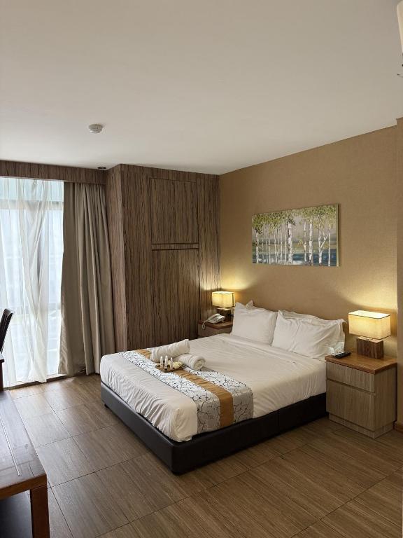 a bedroom with a large bed and a large window at Palette - Bukit Mata Boutique Hotel in Kuching